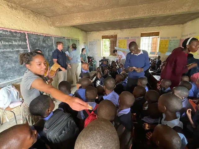 Coggin Church missions team distributing items to students in a packed classroom during a local outreach initiative