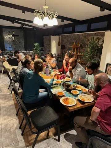 Members of the Coggin Church missions team seated around a dining table enjoying a shared meal during their trip
