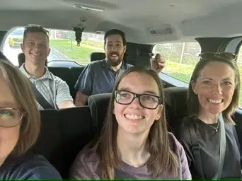 Group of Coggin Church mission volunteers smiling inside a van while traveling during their mission trip