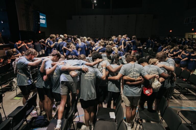 Large group of Coggin Youth students gathered together in prayer during a youth event