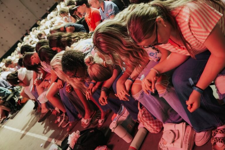 Coggin Youth students bowing their heads together in prayer during a worship gathering